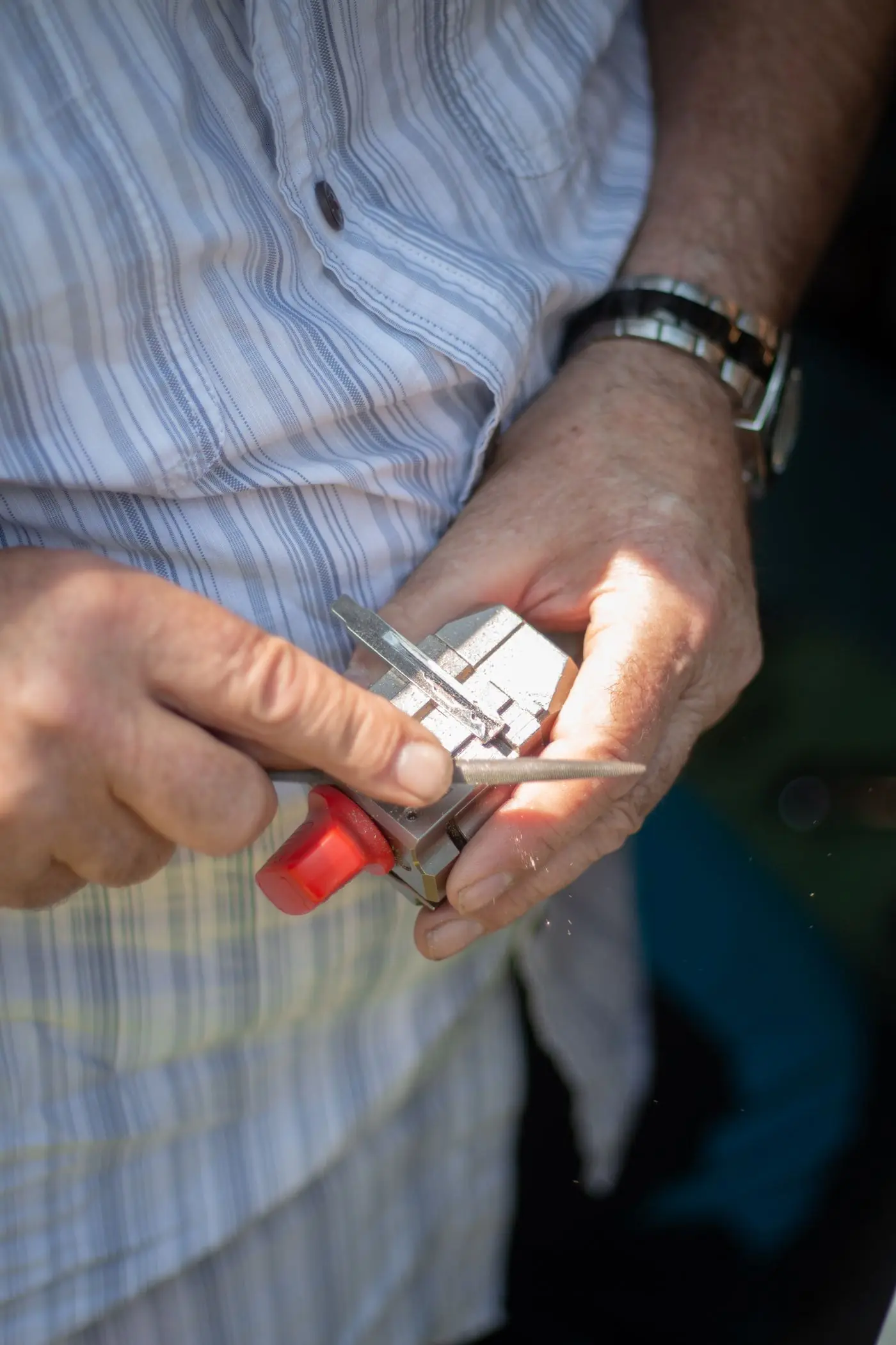 Les mains d'un serrurier en chemise rayée, qui ajuste une clé à la main